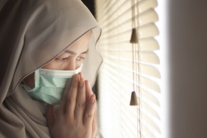 Sad woman in lockdown quarantine due to coronavirus covid 19 pandemic, looking trough window and crying
